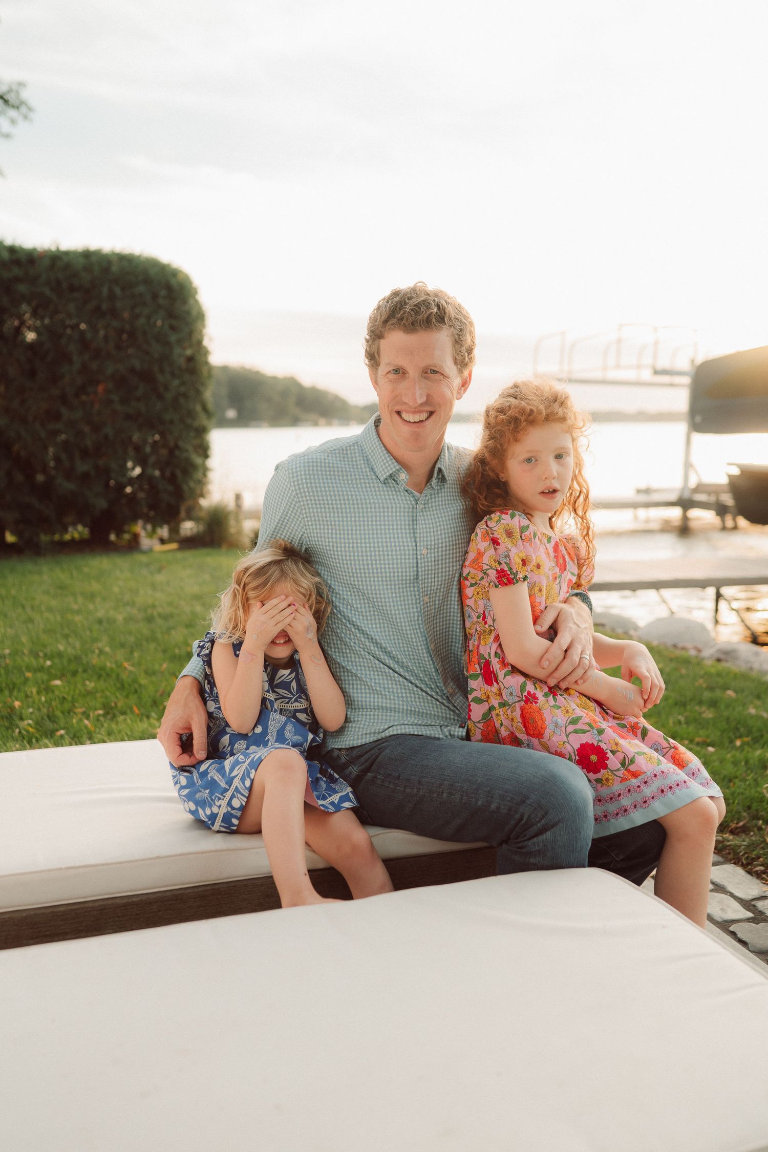 A family shares a playful moment together on a boat deck with water and greenery visible in the background.
