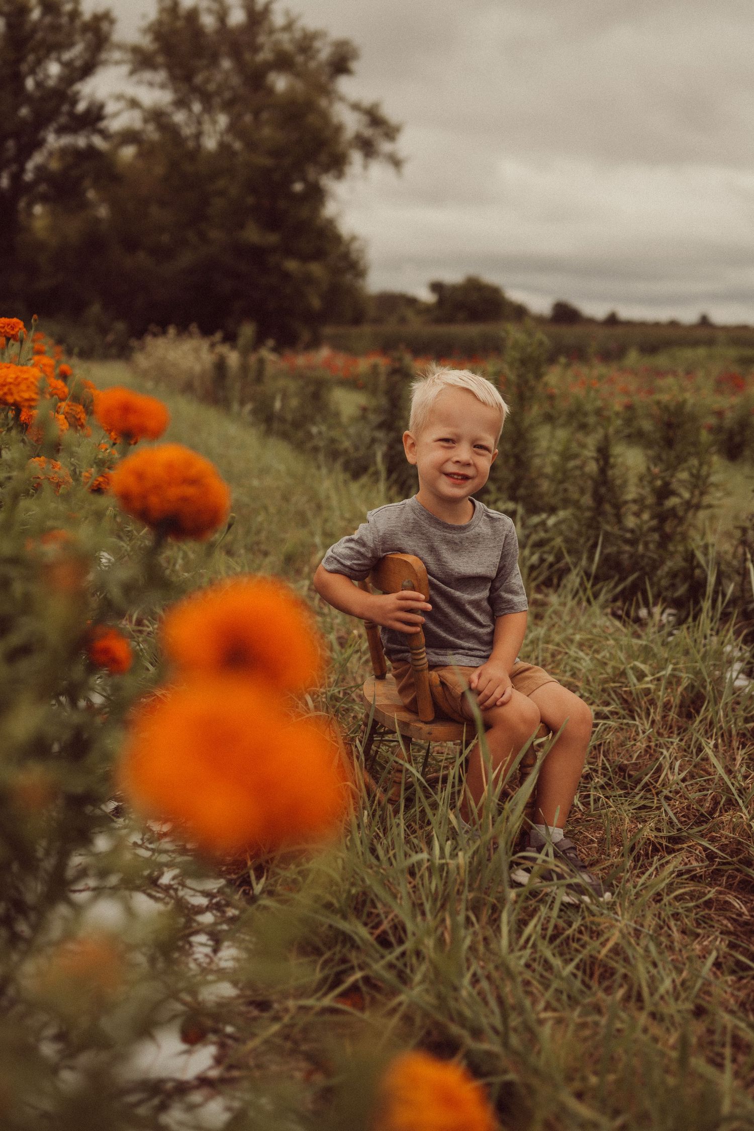 Vibrant orange zinnias frame a joyful summer portrait in a rustic garden setting.