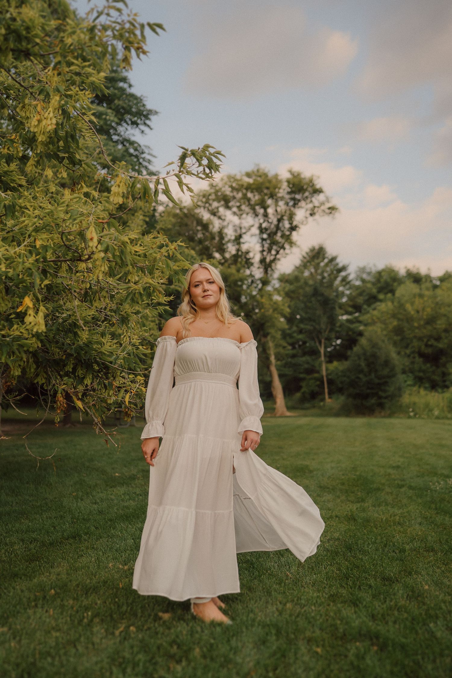A flowing white dress twirls in motion against a natural green backdrop during golden hour.