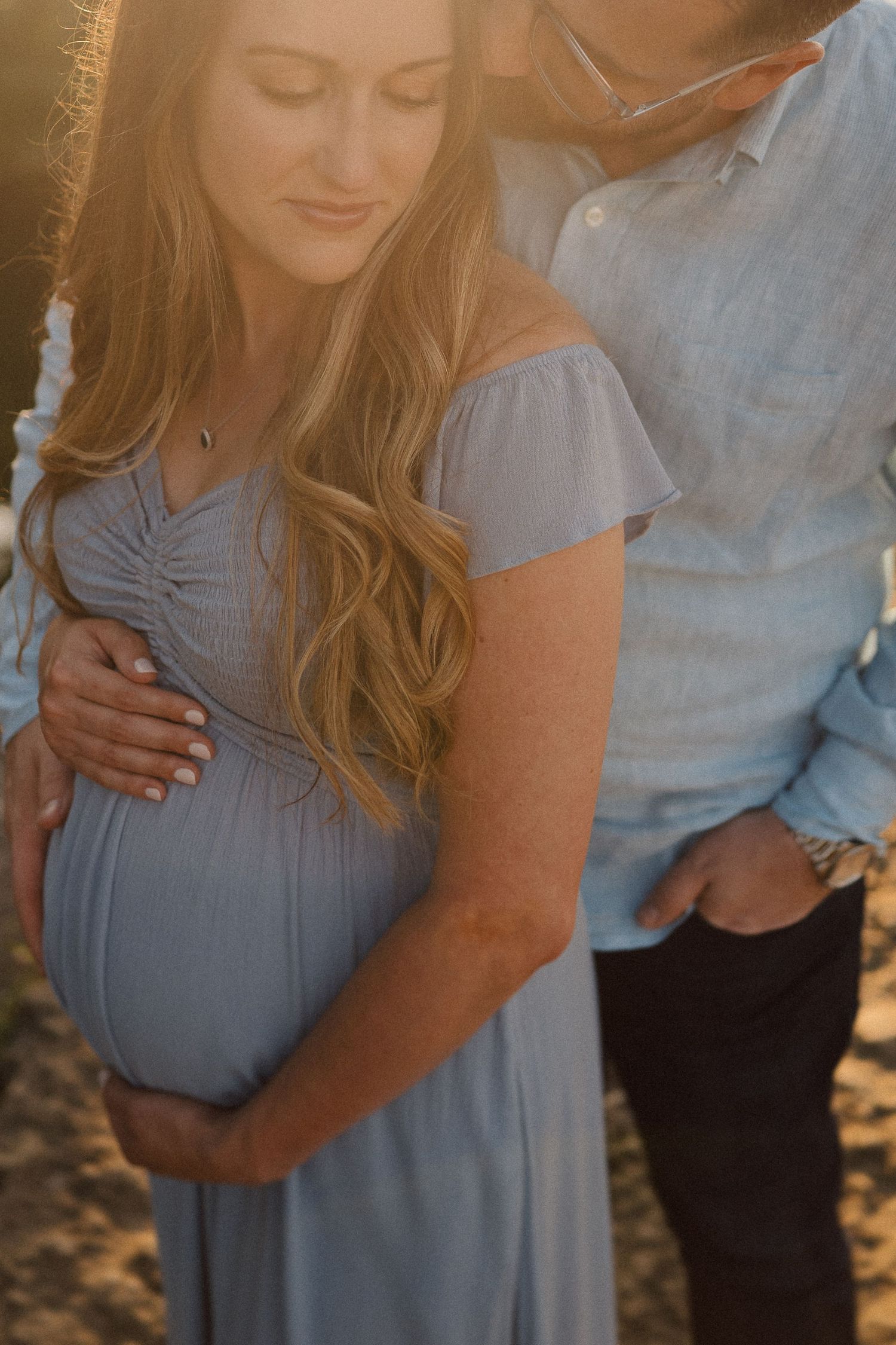 Close up maternity photos show a couple sharing tender moments in soft afternoon lighting.