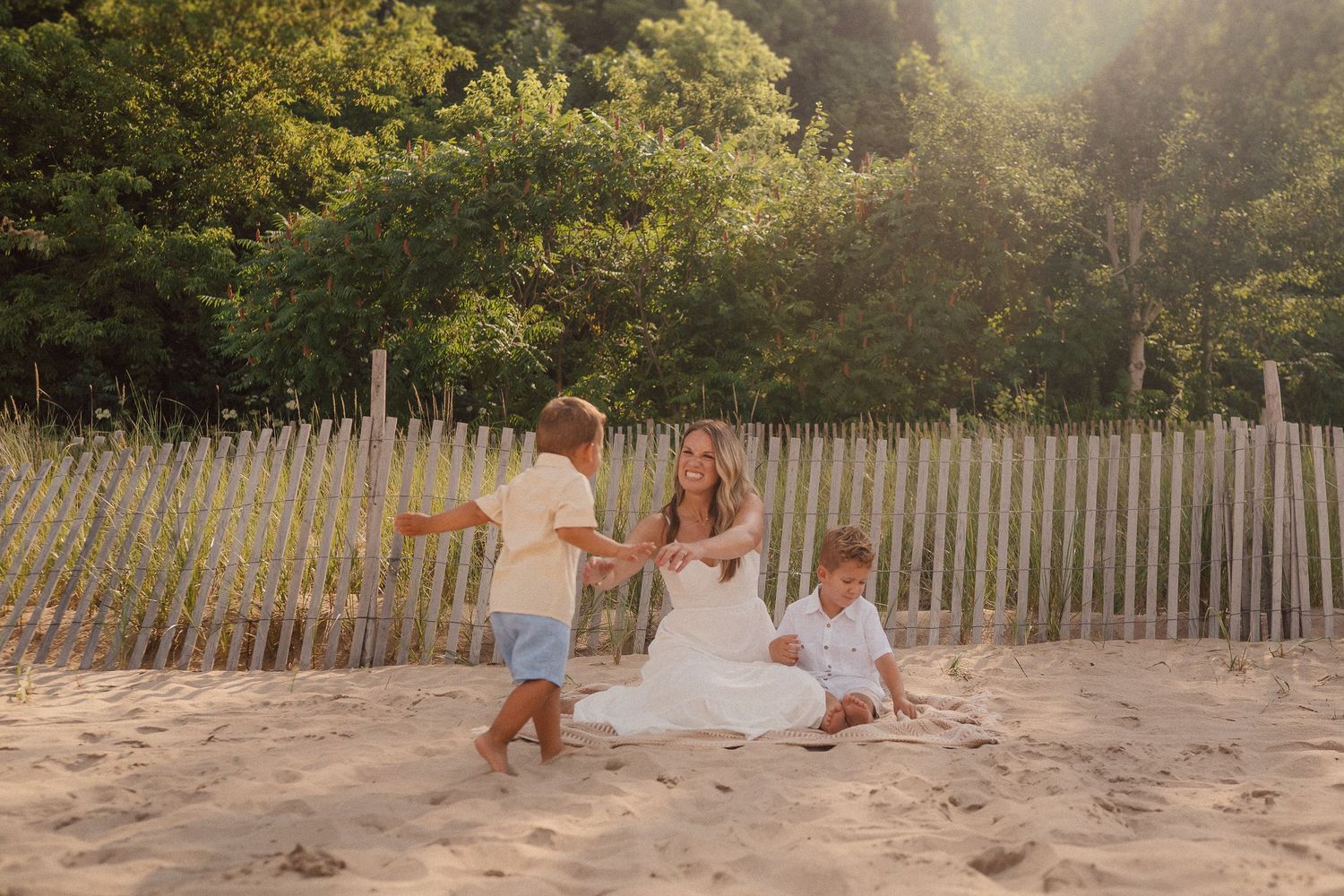Scenic beach portrait with wooden fence and lush greenery in background.