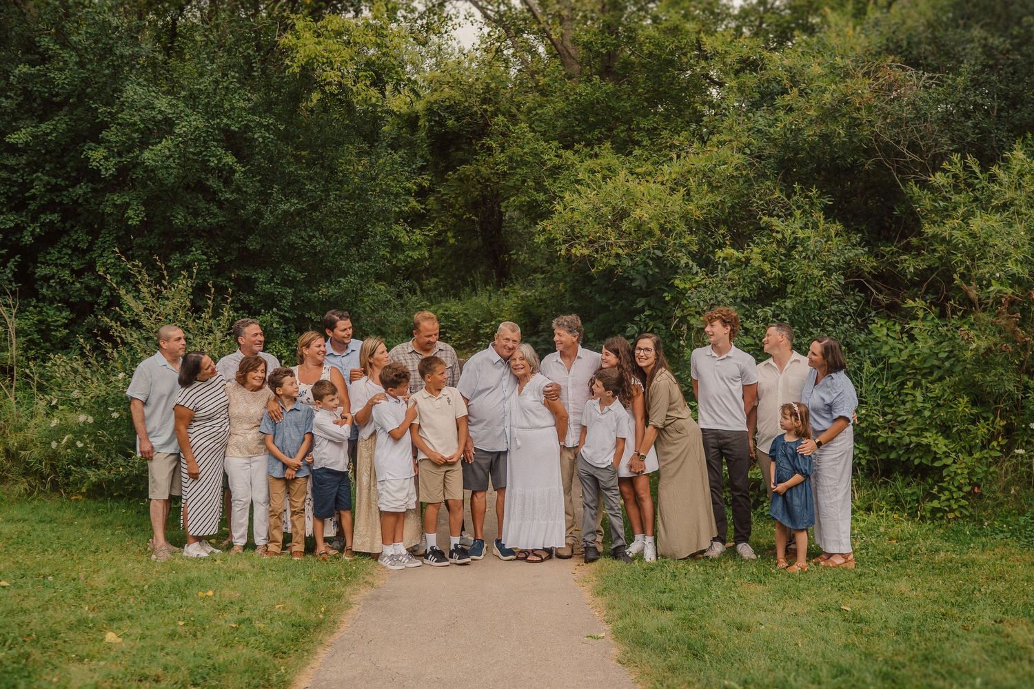 Large family group photo outdoors with everyone wearing coordinating neutral colors.