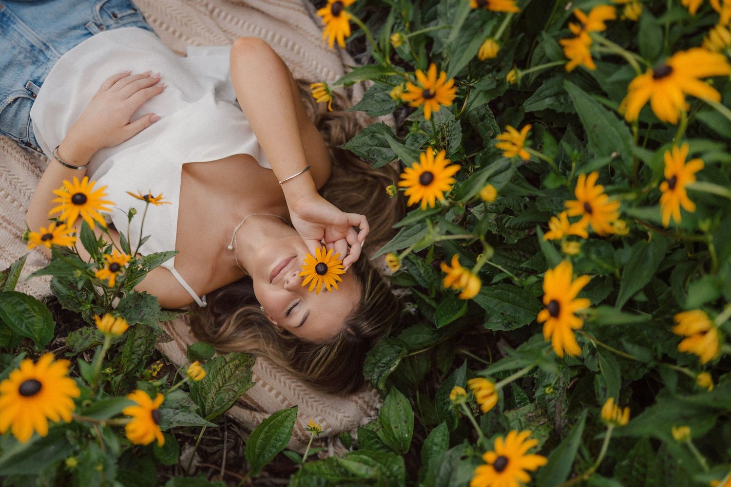 Hands gently touching yellow sunflowers in garden during golden hour.