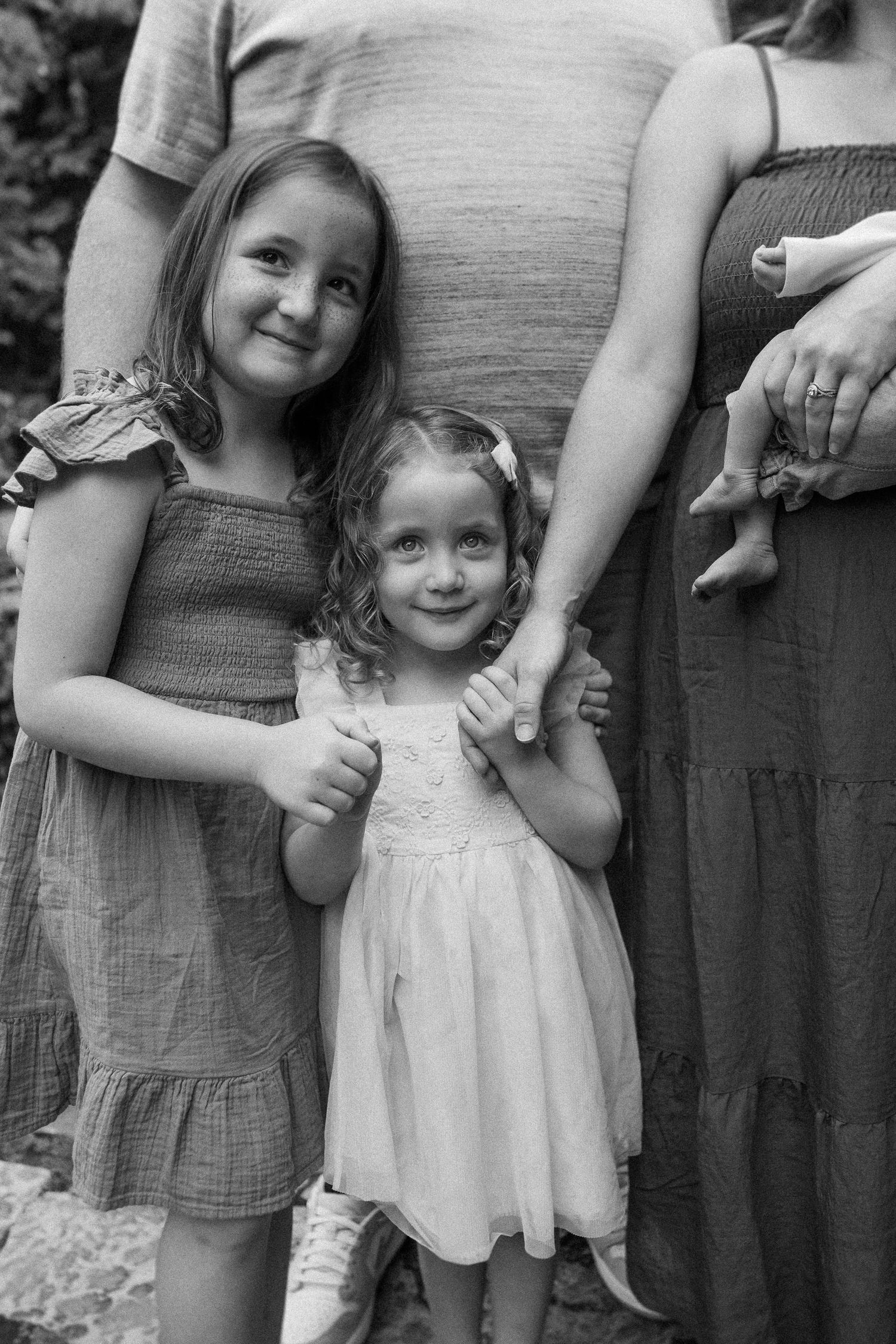 Two young children standing together in casual clothing, shot in black and white.