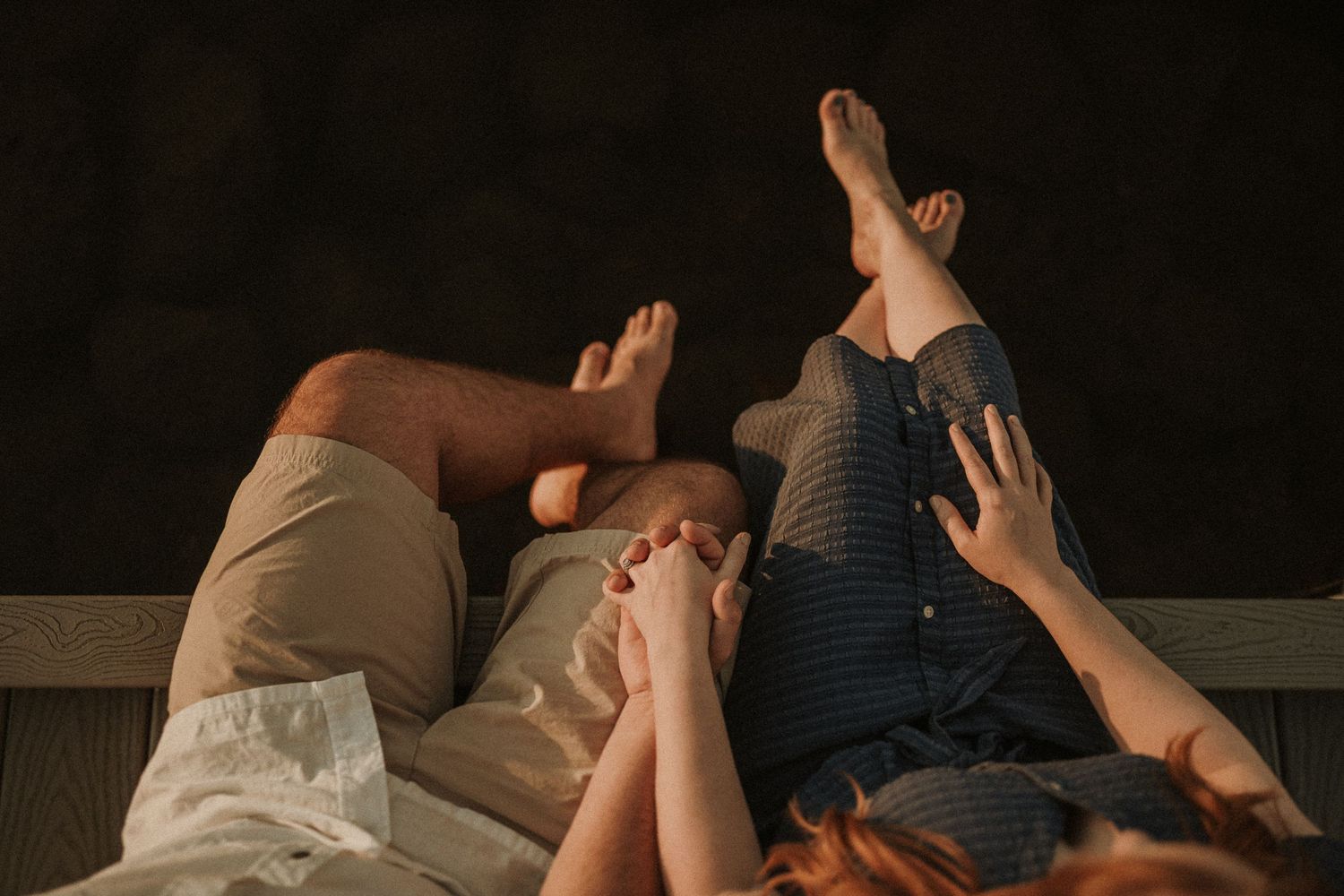 Feet and hands visible as people lay relaxing together on a dark surface.