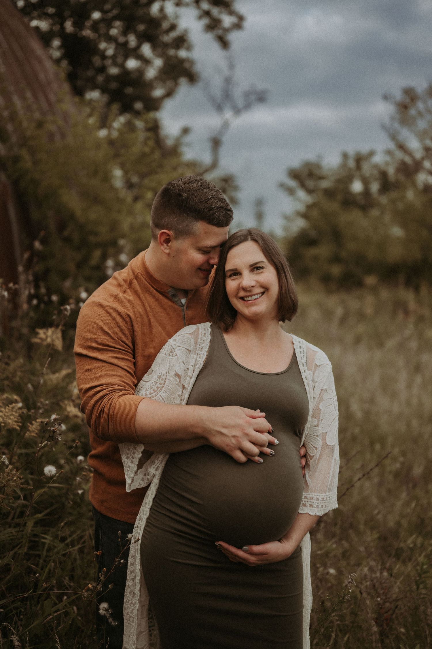 An intimate maternity portrait against a rustic barn backdrop.