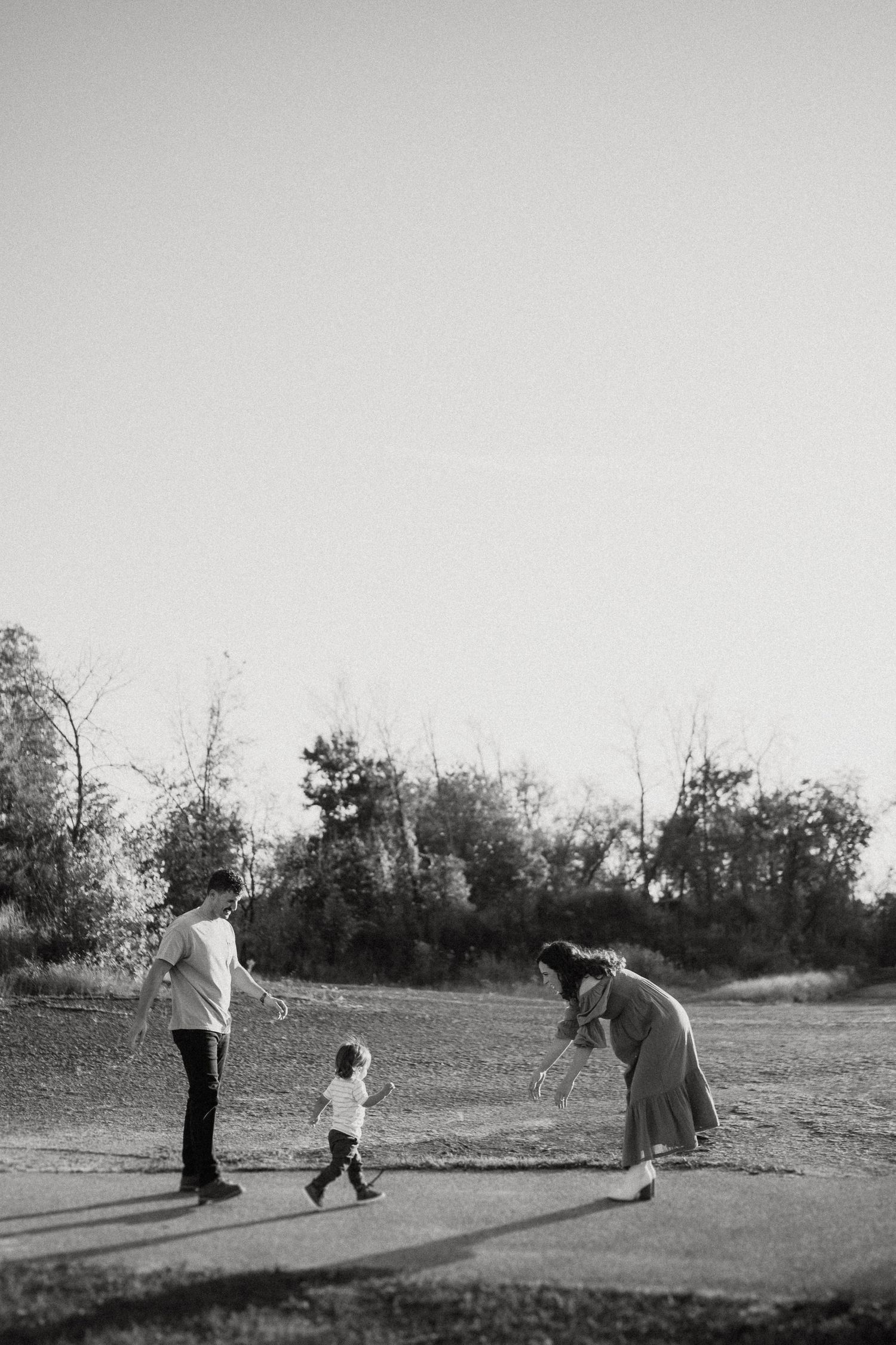 Black and white image of three people walking together on a dirt path.
