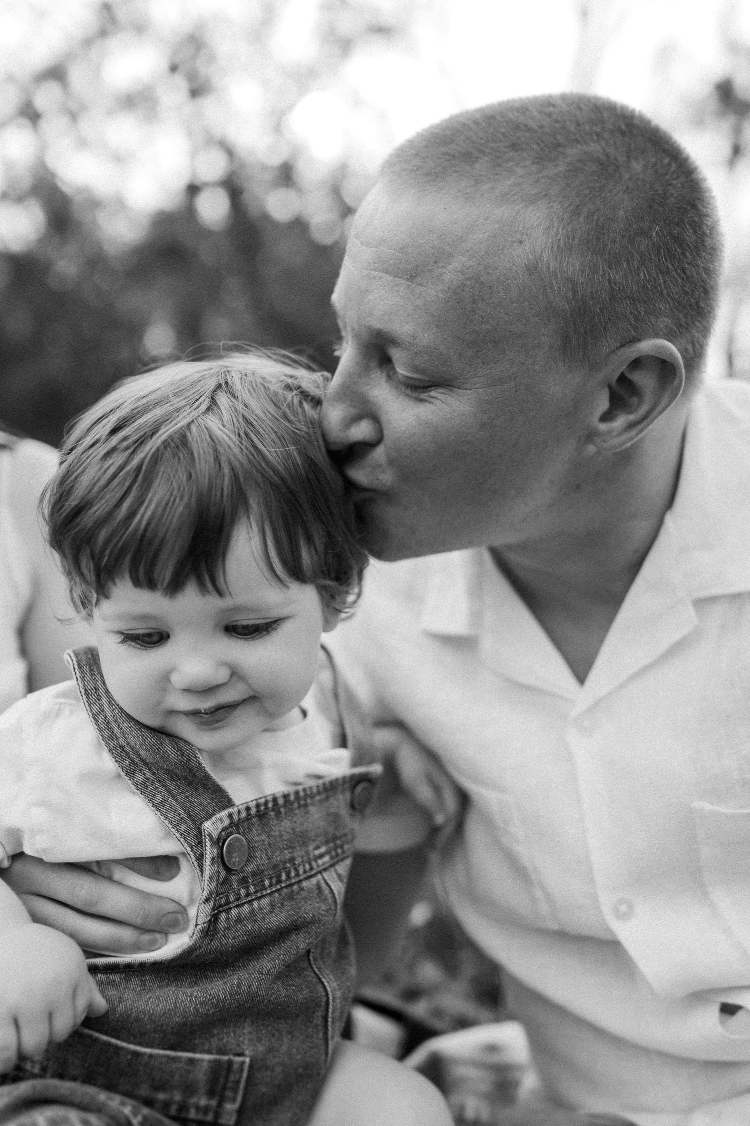 Black and white series showing tender bonding moments between father and child in close-up portraits.