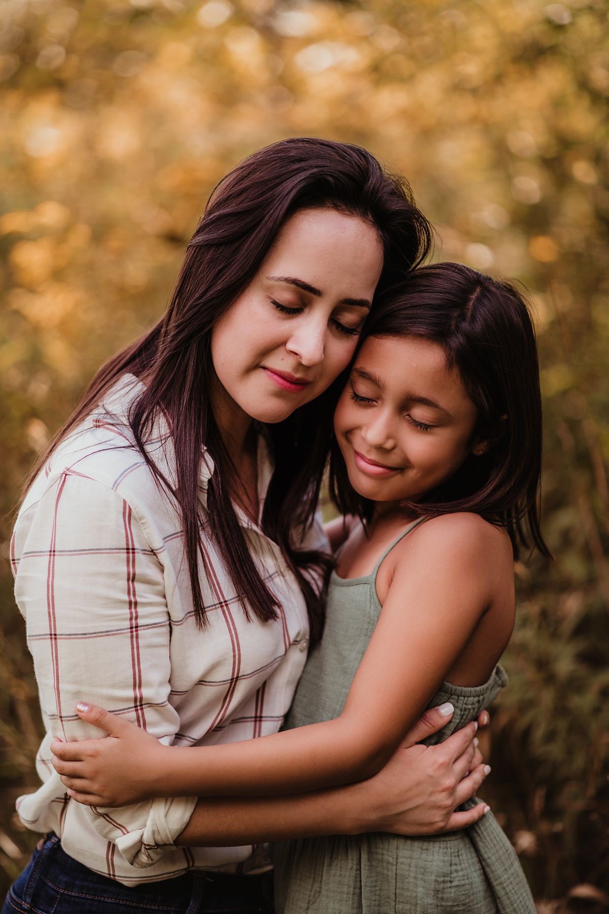 Tender embrace between parent and child outdoors with warm autumn lighting.