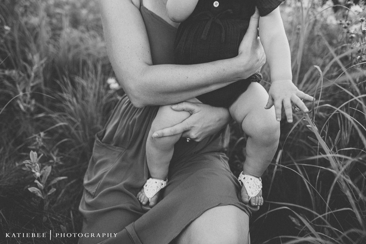 Black and white portrait showing a close embrace in tall summer grass.
