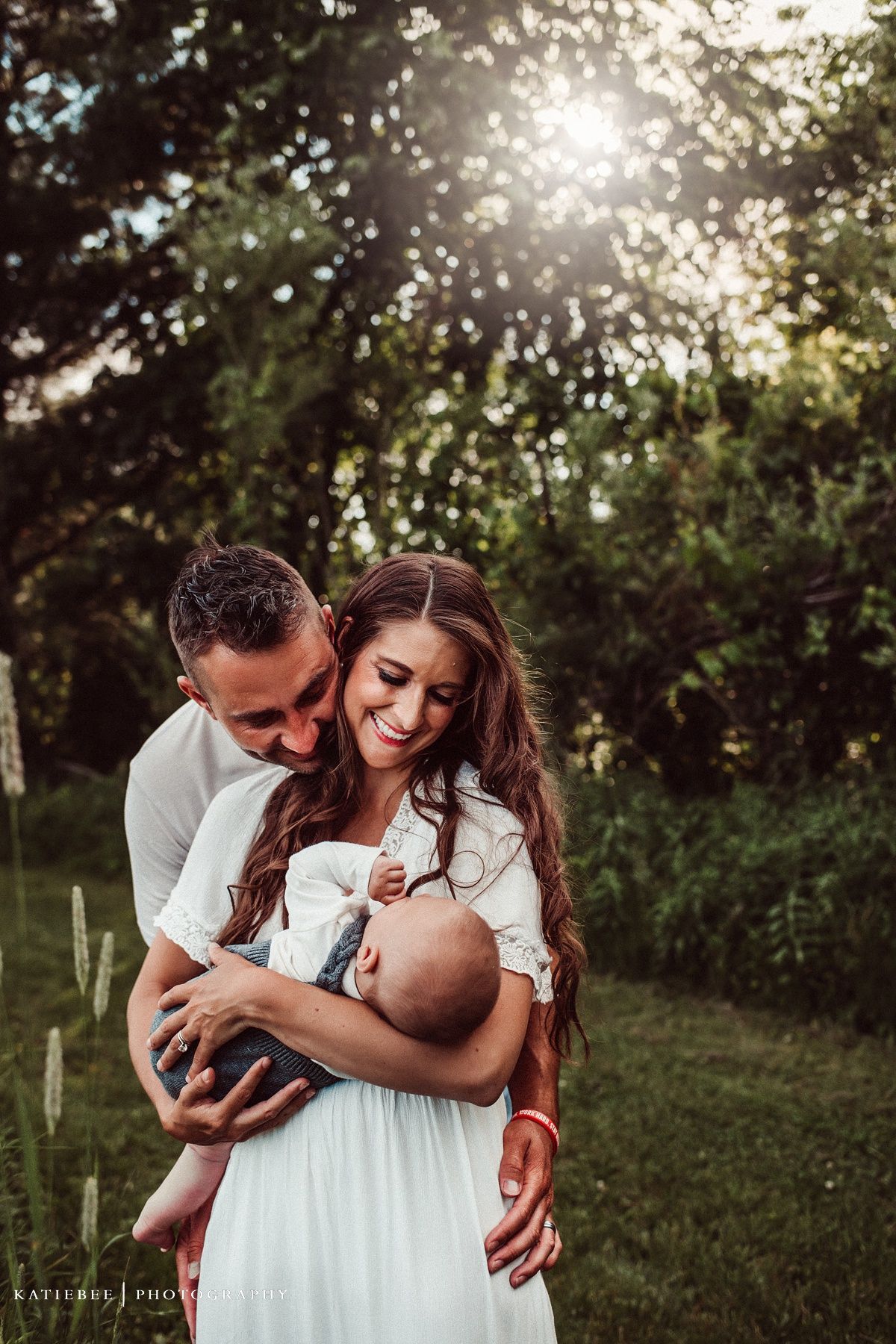 Intimate family portrait in a sun-dappled garden with golden light filtering through trees.