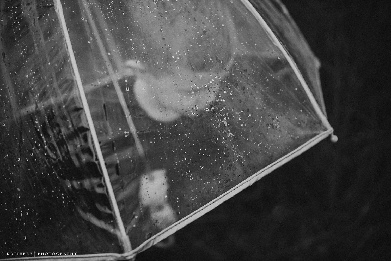Rain drops on clear umbrella with dark moody background.