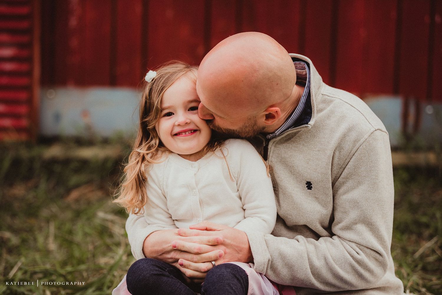 A touching moment of affection shared against a bright red barn background.