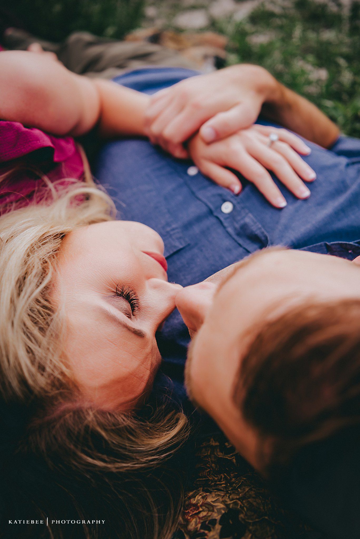 Intimate close-up shot of couple lying in grass during golden hour.