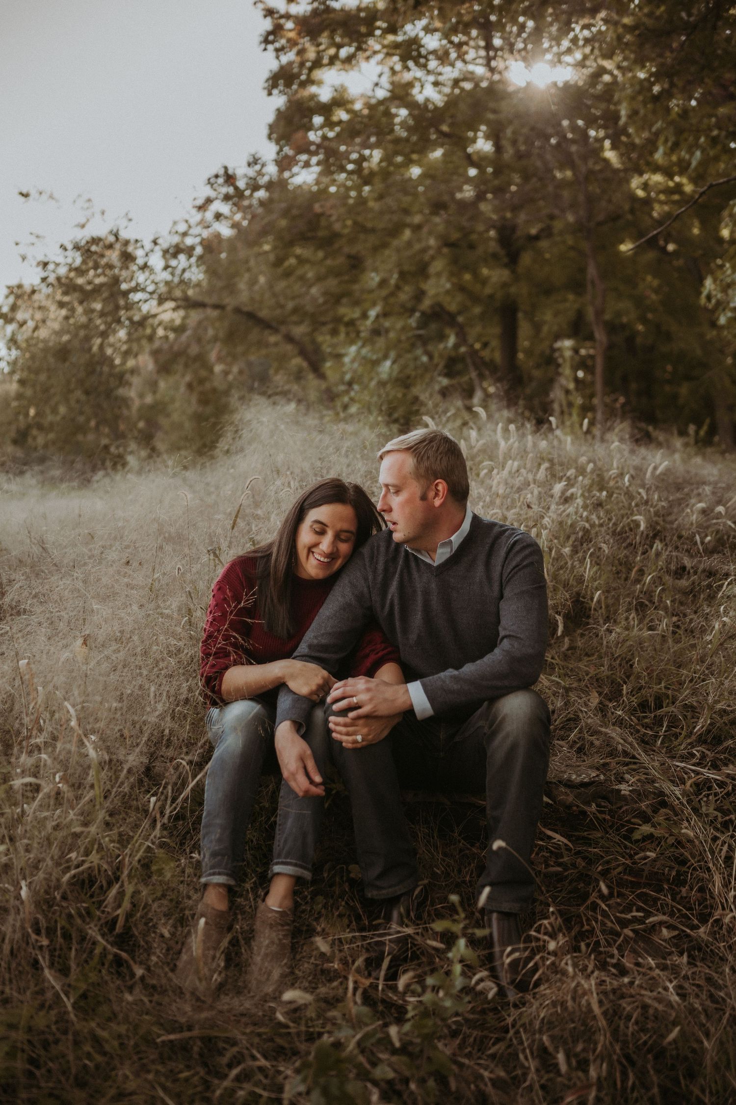 An intimate couples portrait session in a moody autumn field with golden sunlight filtering through trees.