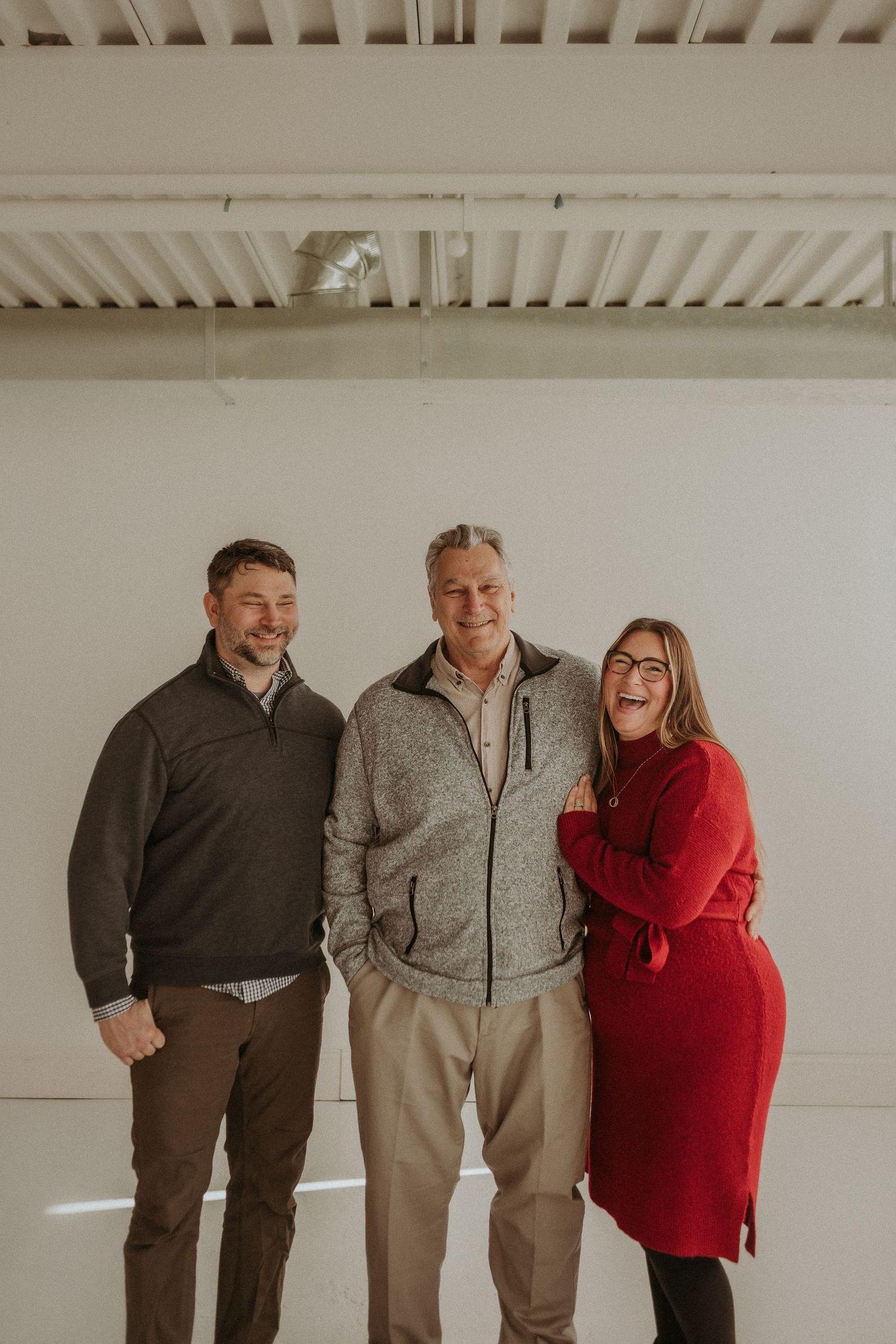 Three people pose together in coordinated outfits against a white studio backdrop.