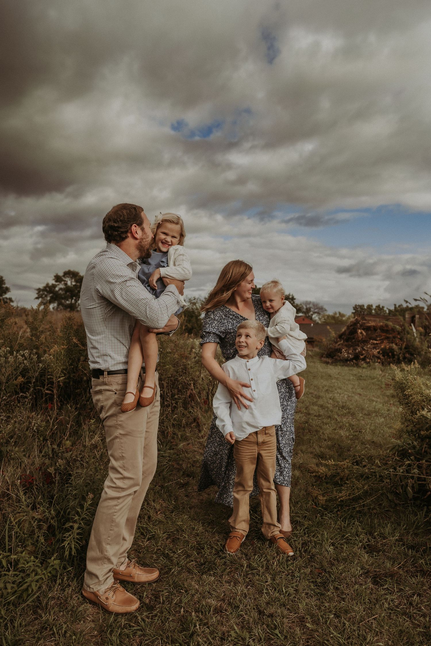 Casual family lifestyle portrait against a backdrop of stormy skies and wild grass.