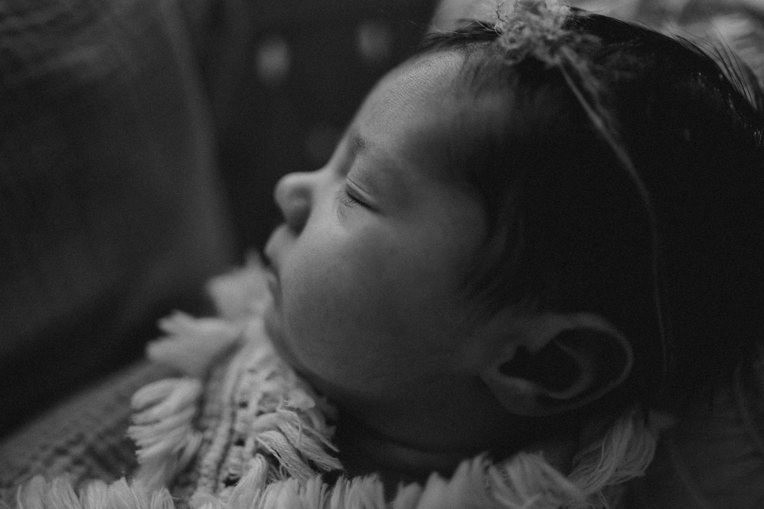Close-up black and white portrait of sleeping infant wearing a delicate headband.