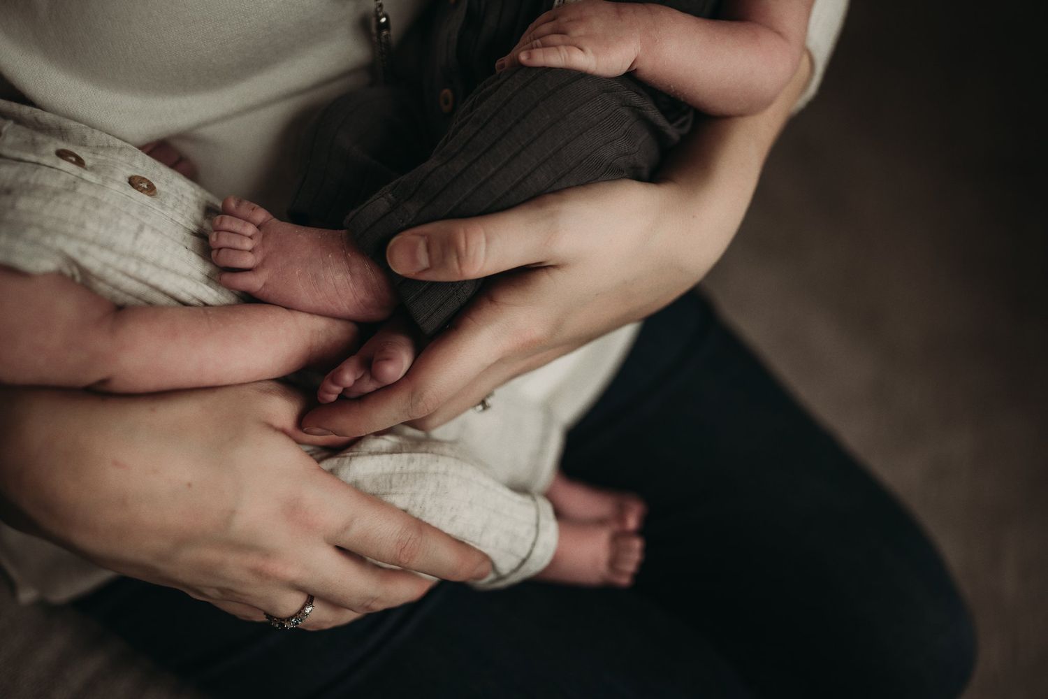 Close-up shot of gentle hands holding tiny baby feet in soft lighting.