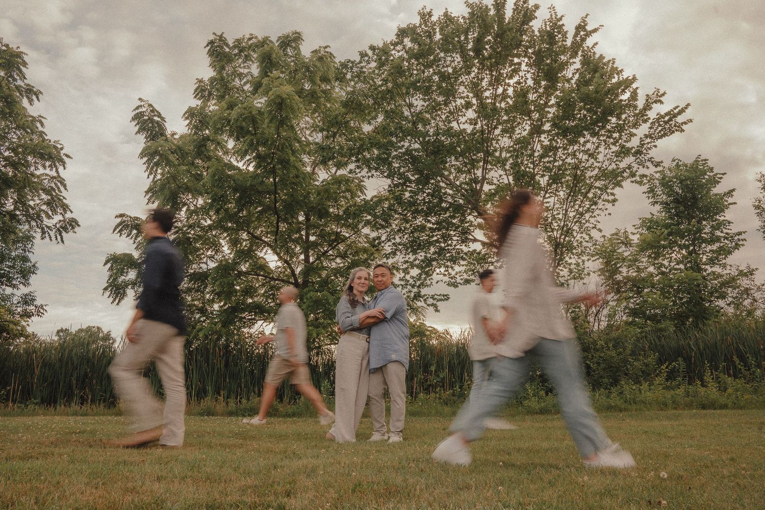 Candid family photo with motion blur of members walking in a grassy outdoor setting.