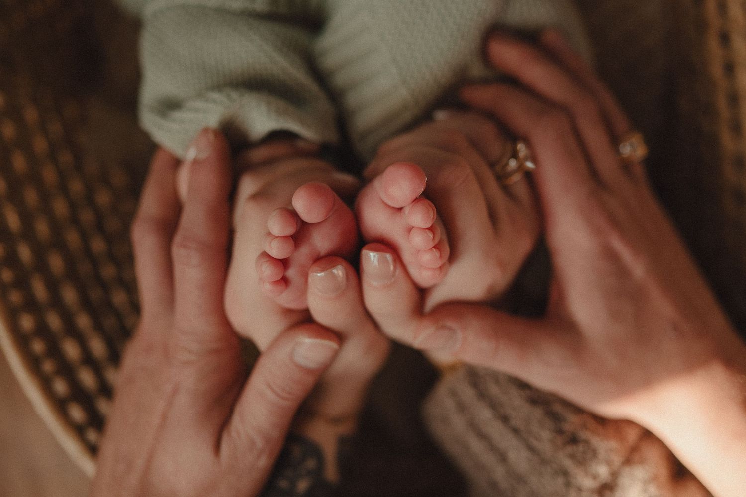 Close-up detail shot of tiny baby feet being held by adult hands.