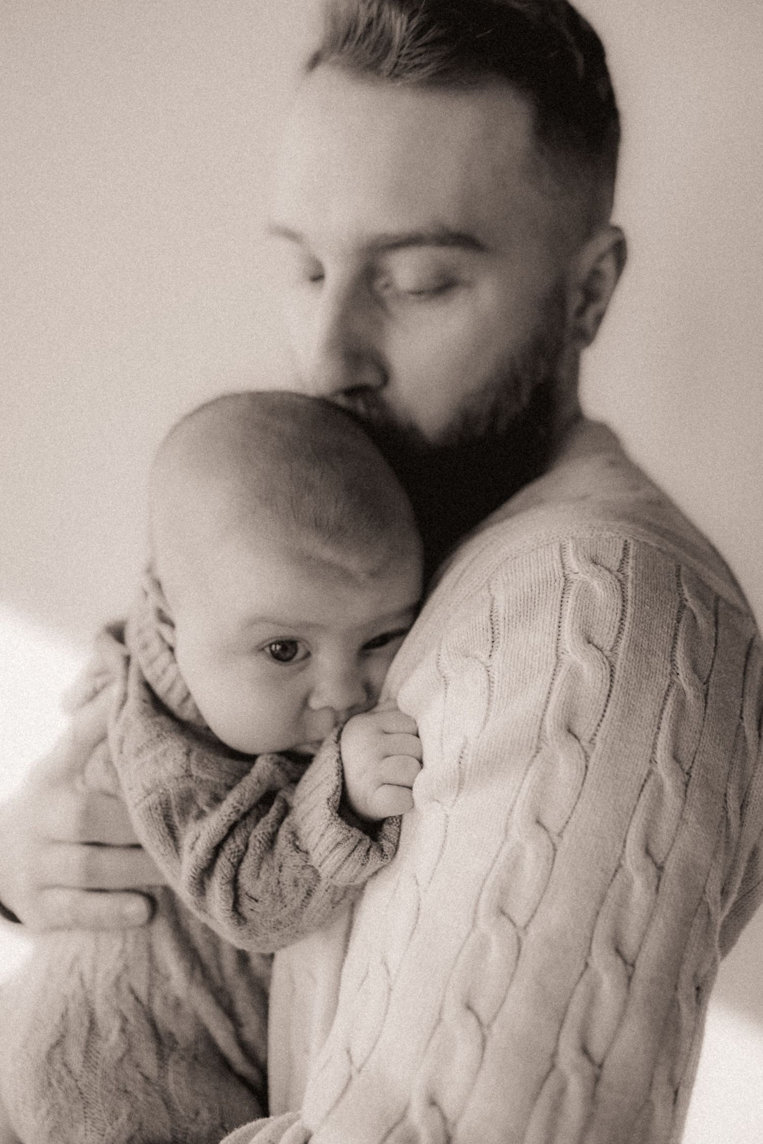 Close-up photography of baby snuggling in cable knit sweater.