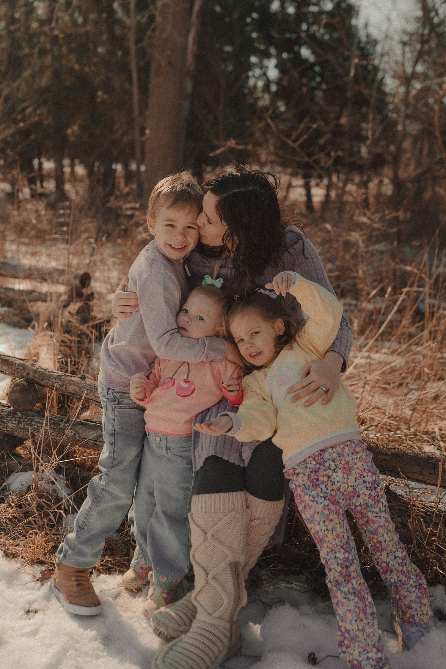 A cozy family photoshoot in warm tones against a snowy winter backdrop.