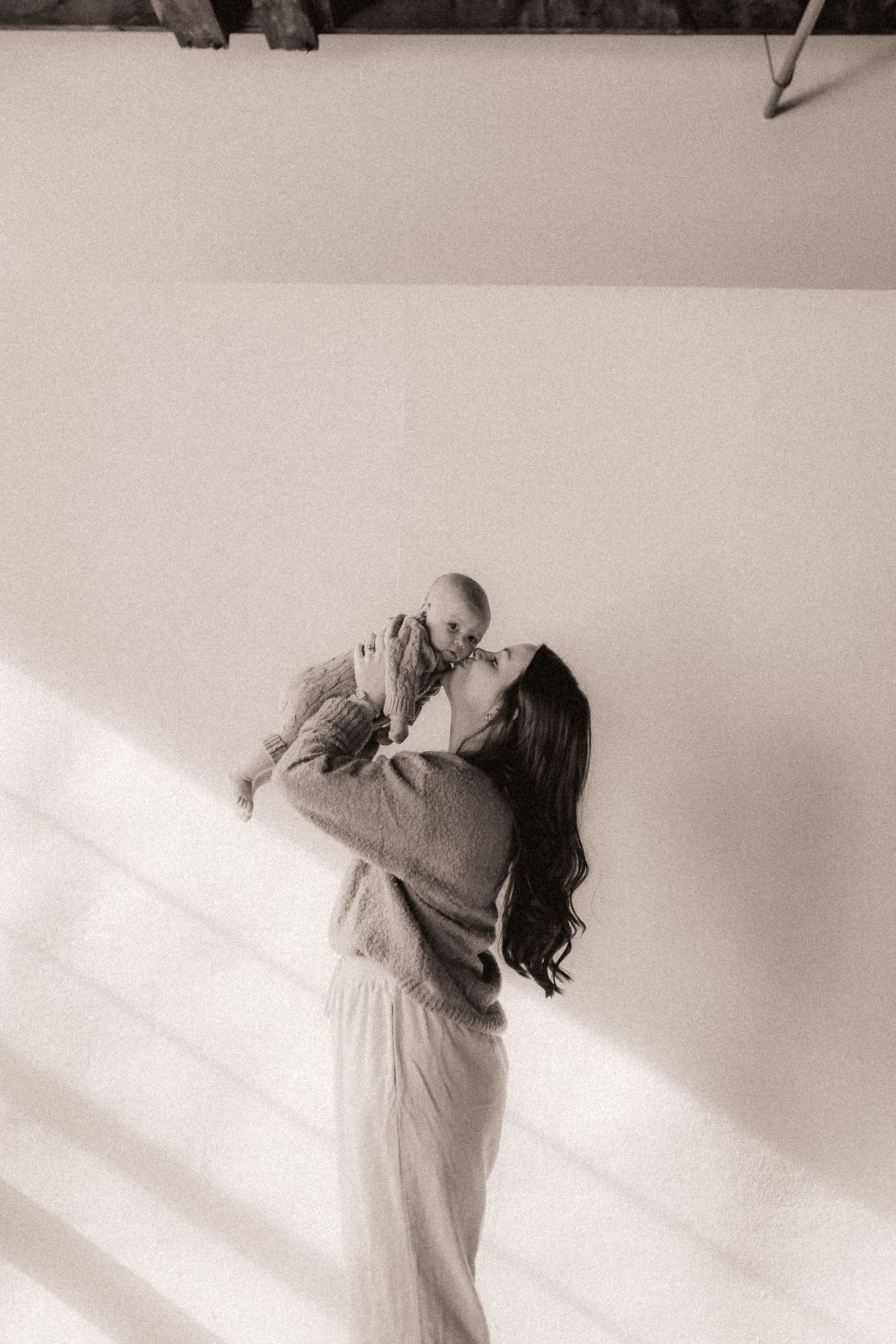 Minimalist photography sequence capturing intimate family moments against a white wall with dramatic shadows.