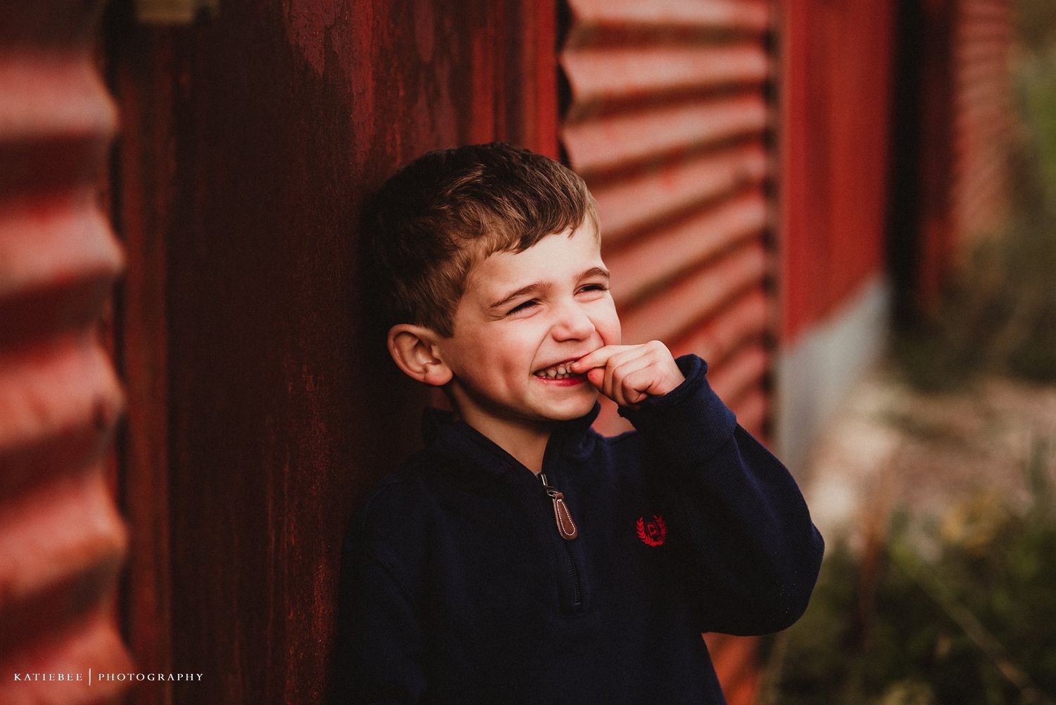 Candid moment of laughter against rustic red barn siding.