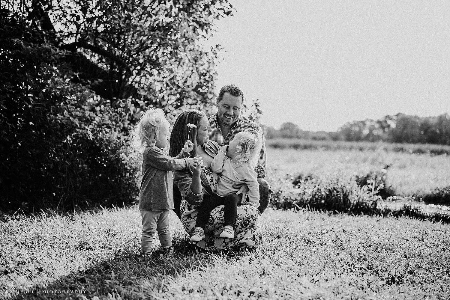 A black and white image of a family sharing a candid moment outdoors.