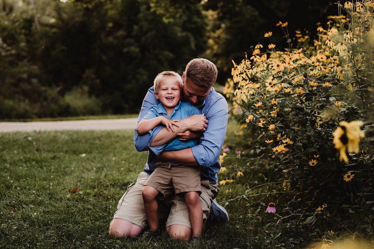 Heartwarming moment of affection in garden setting with yellow flowers blooming in background.