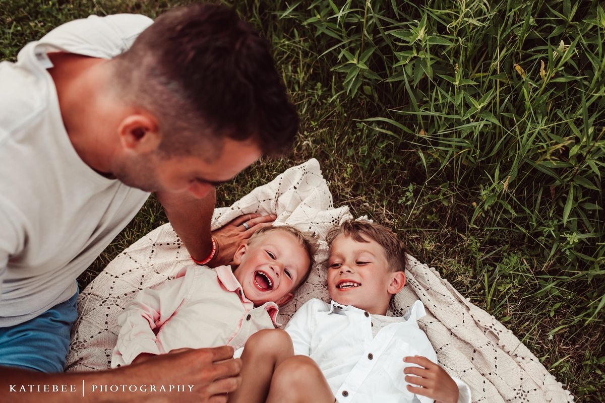 A joyful family moment captured as they lay together on a blanket in the grass.