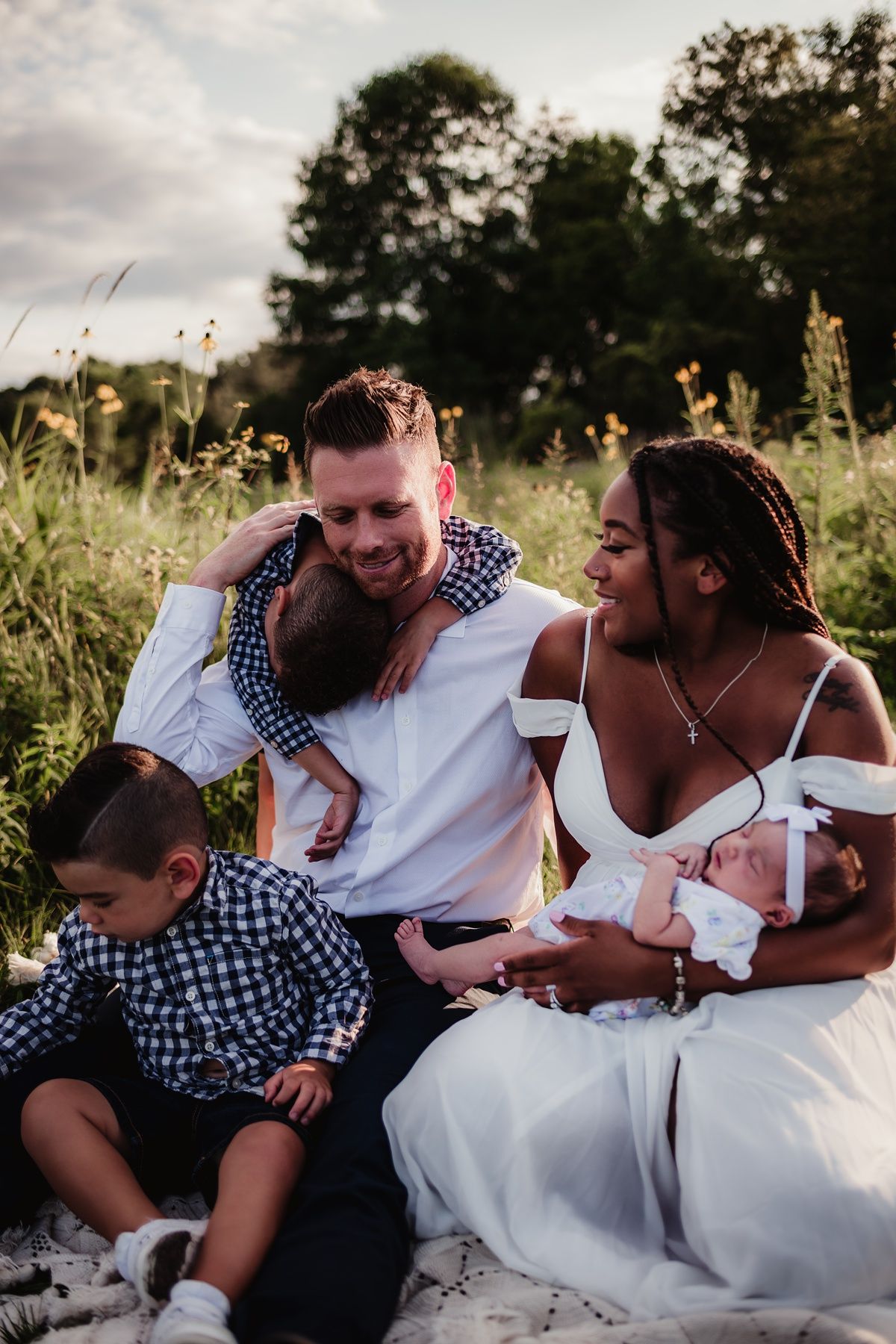 Beautiful outdoor family portrait on a blanket with a newborn baby at sunset.