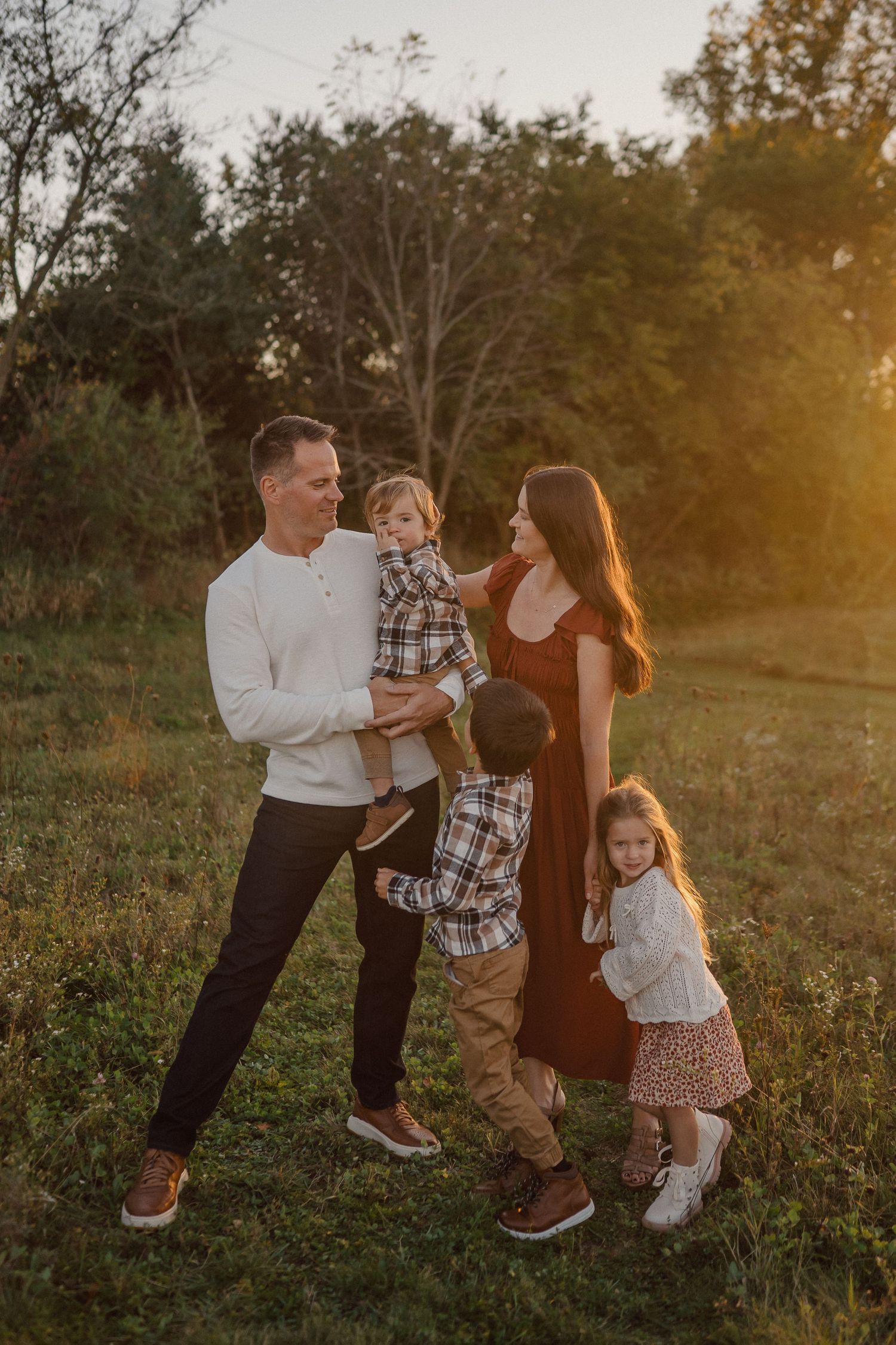 A playful outdoor family photoshoot in a meadow at sunset.