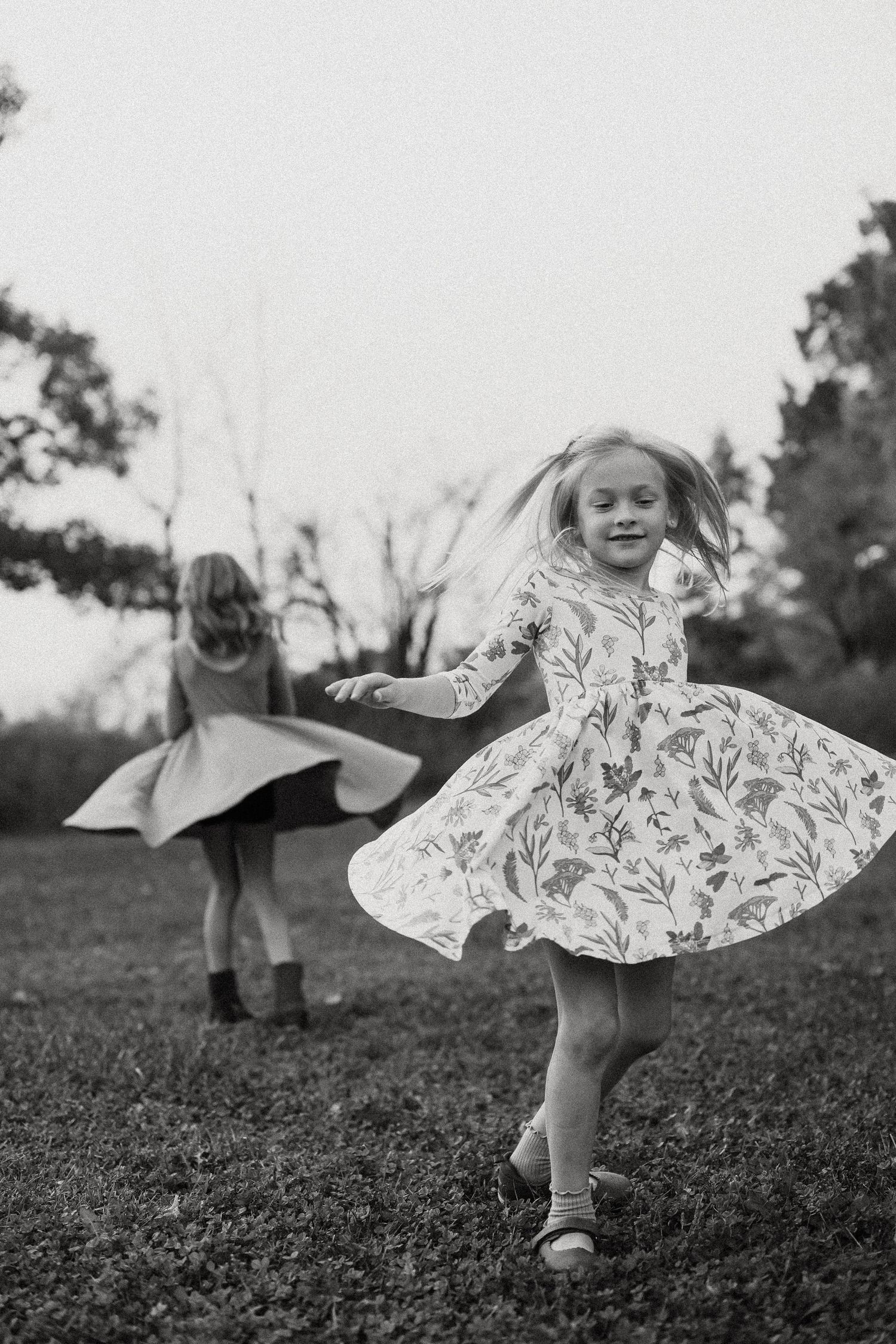 Black and white photo of a twirling dress in motion against a natural outdoor setting.