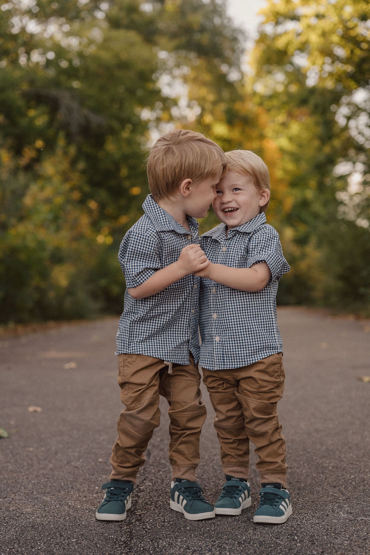 Two young children in matching outfits share a sweet moment together on a path.
