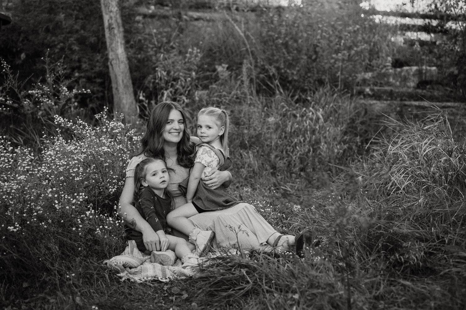 Black and white image of people relaxing on blanket in grassy outdoor setting.