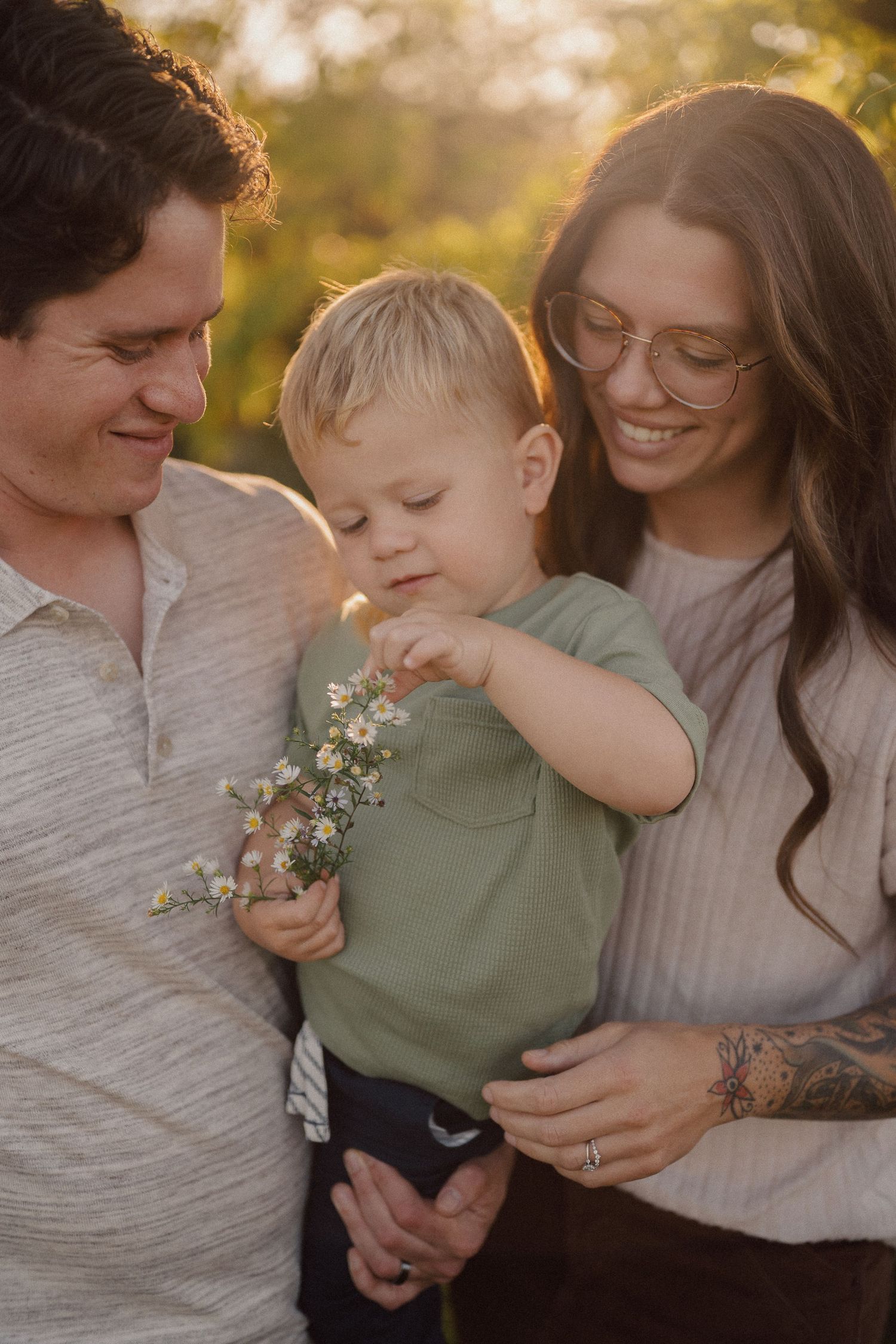 Family embracing and laughing together during sunset photoshoot with delicate wildflowers.