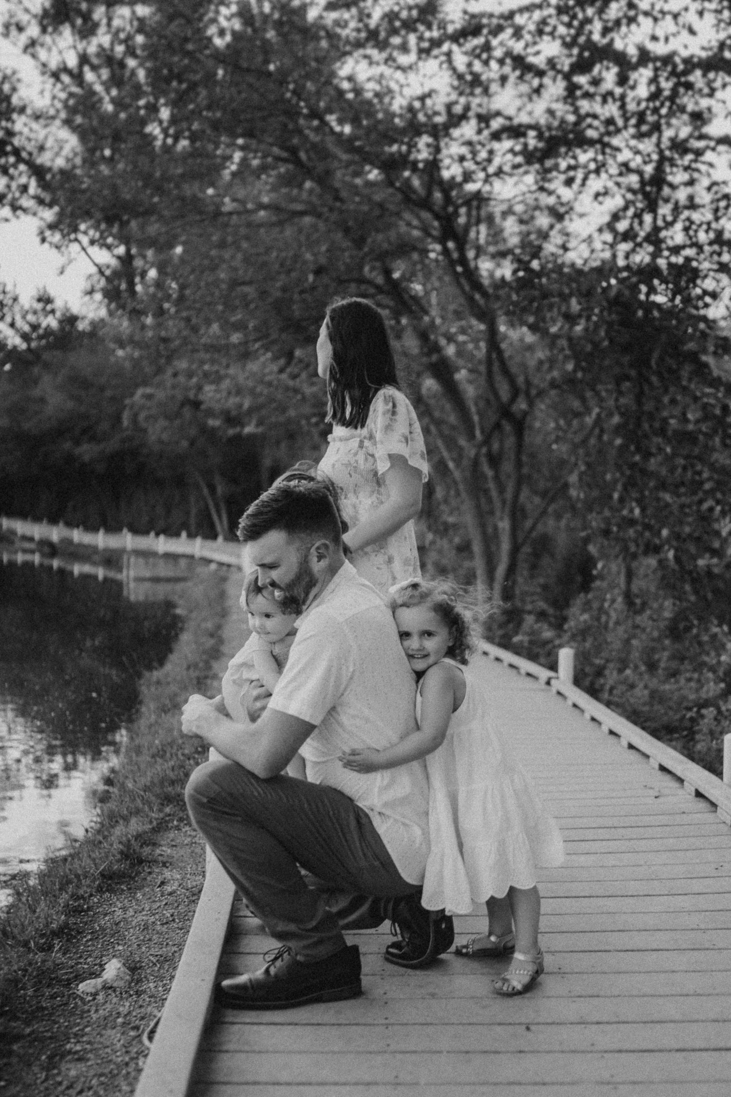 A heartwarming moment captured on a wooden boardwalk overlooking a peaceful river.