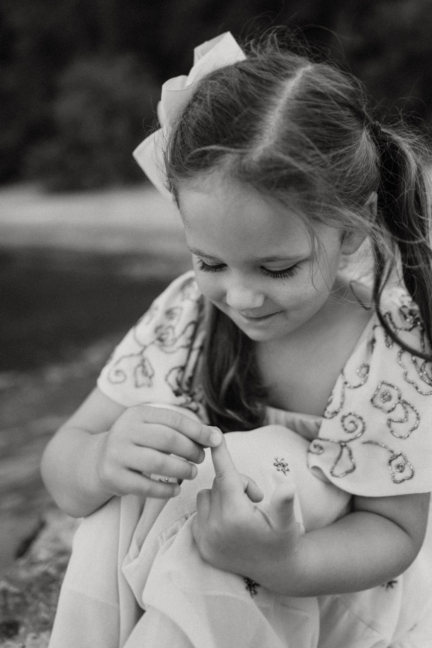 Black and white closeup of child examining something with gentle smile.