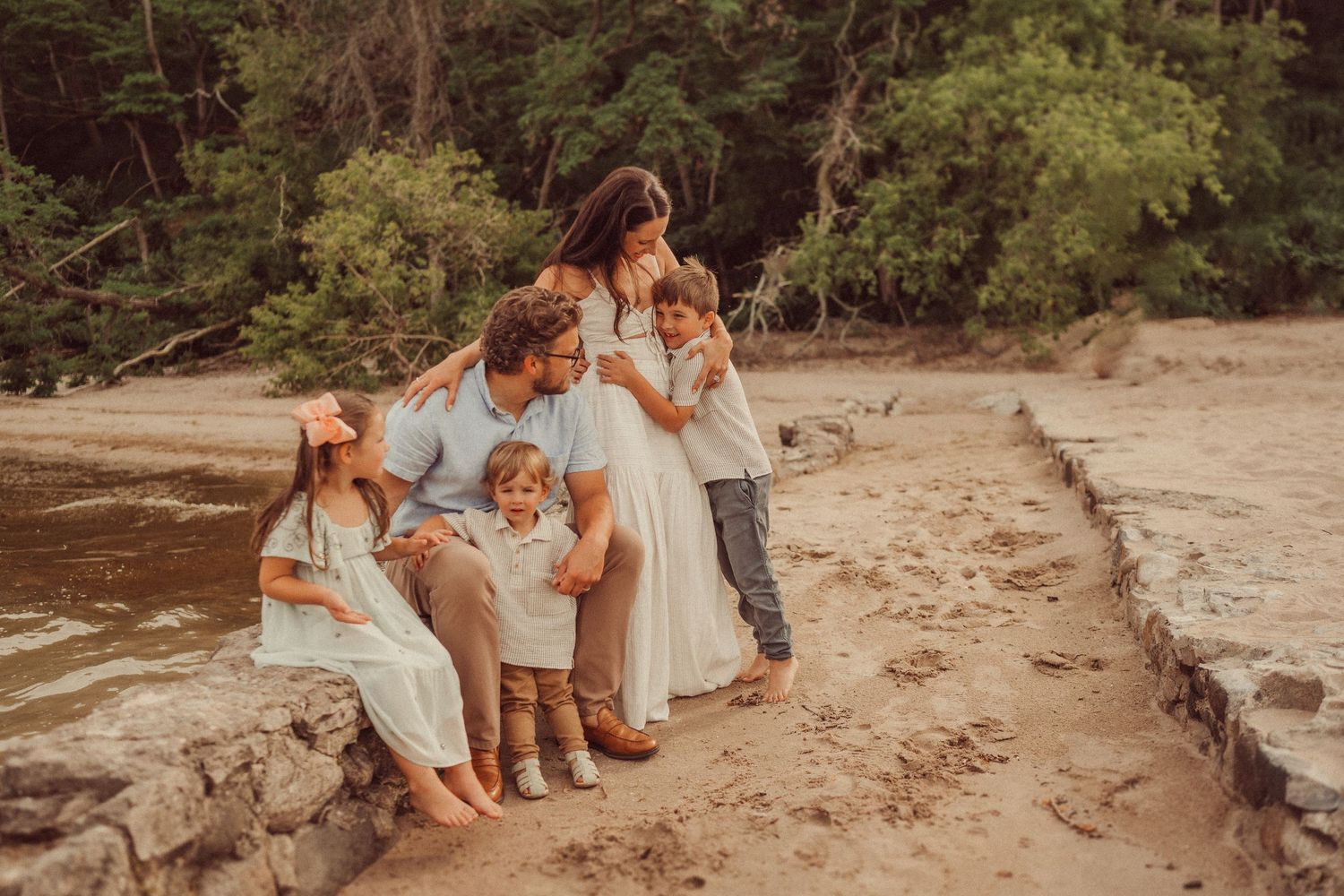 Family sitting together on coastal rocks during a sunset beach photoshoot.