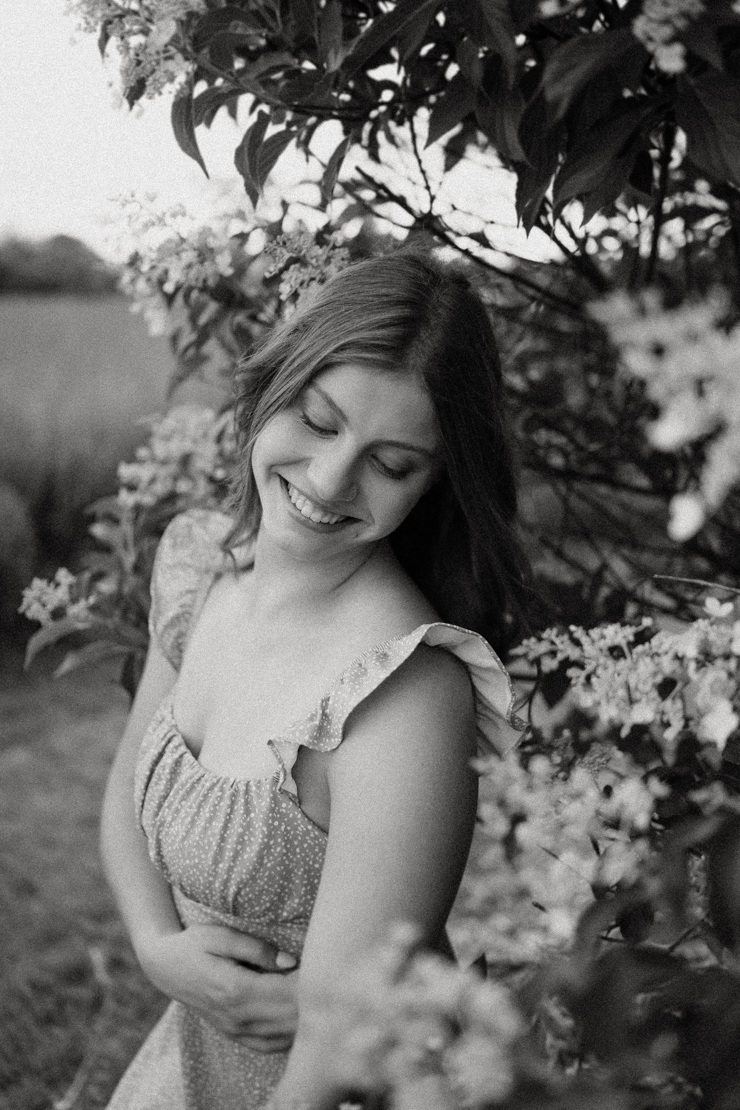 Black and white portrait through flowering branches with soft natural lighting.
