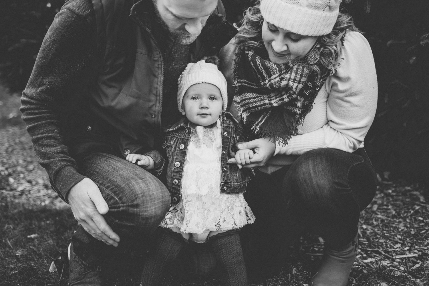 Black and white portrait of family in winter attire sitting together outdoors.