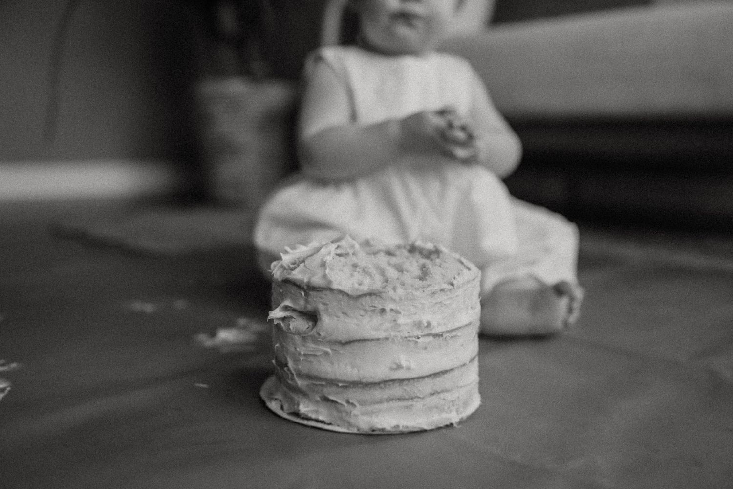 Black and white close-up of a simple tiered cake during a smash cake photo session.