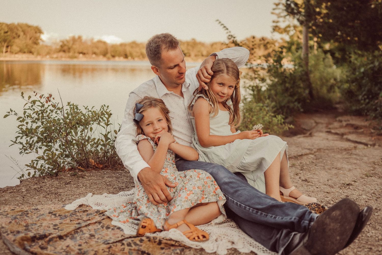 Tender family moment captured during sunset photoshoot by lakeside.