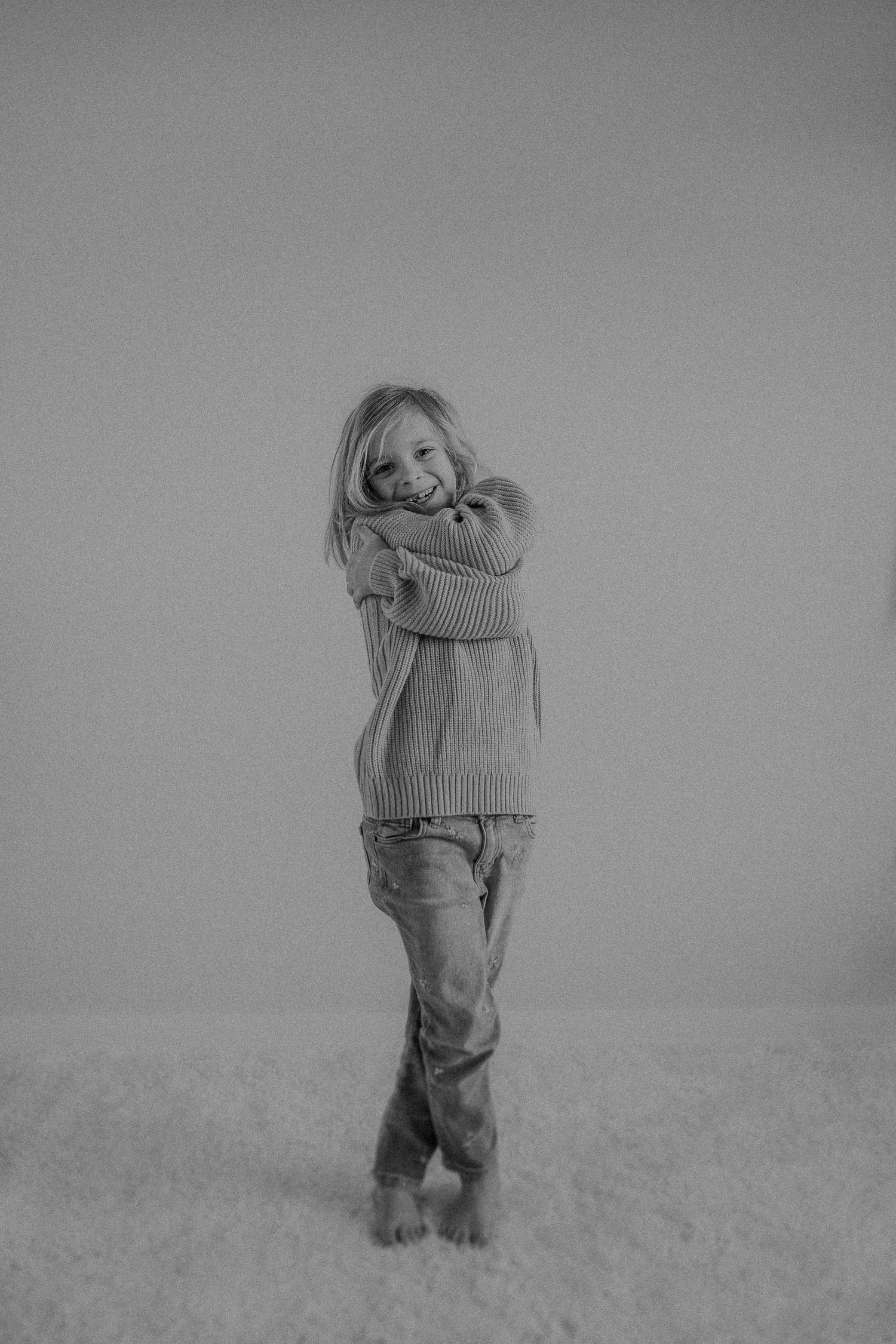 Candid black and white photo of joyful movement while wearing casual knitwear.