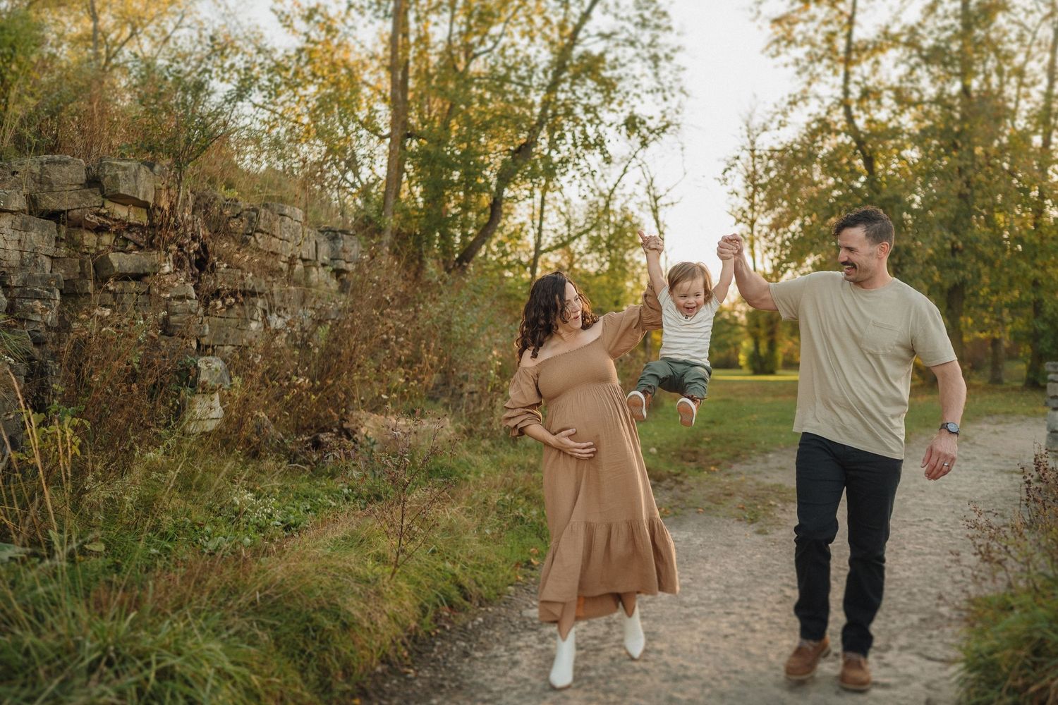 A family enjoys a playful moment together on a walking path surrounded by autumn foliage.