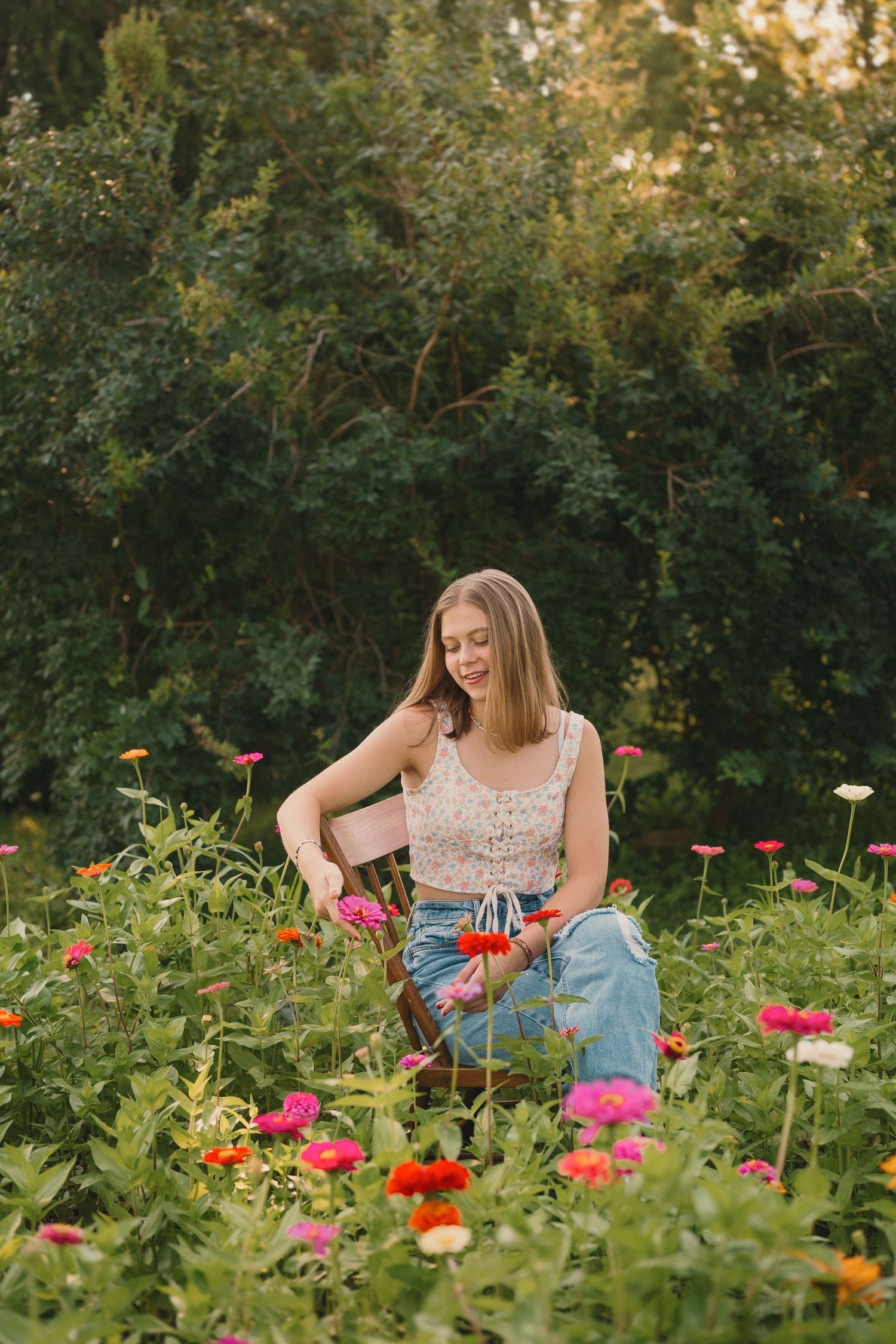 A summer garden scene with colorful zinnias and wildflowers in full bloom as someone sits among the flowers.