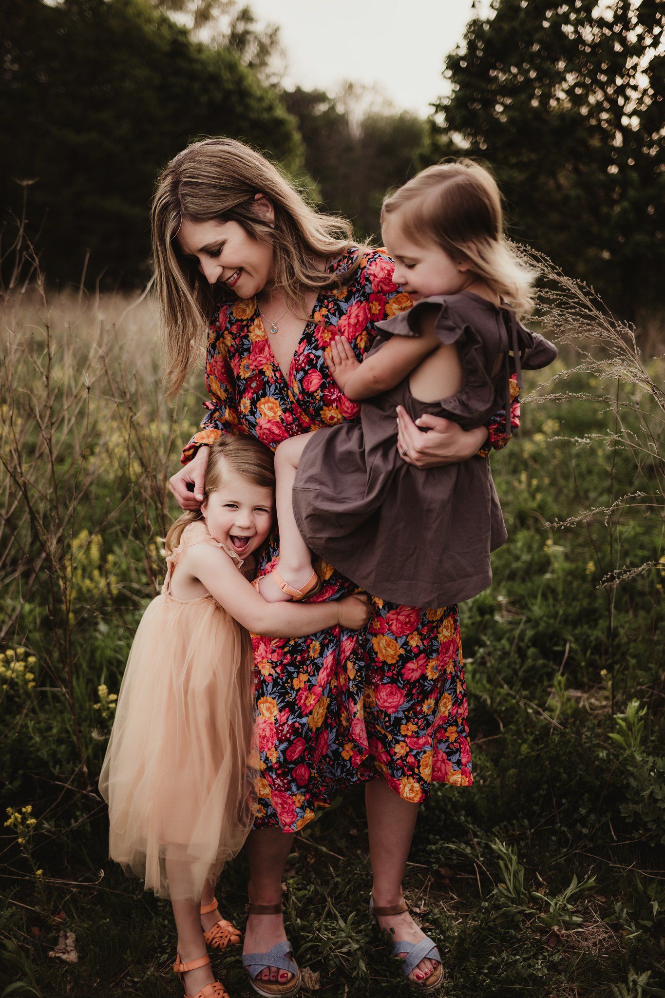 Tender family embrace in a wildflower field wearing floral and neutral colored dresses.