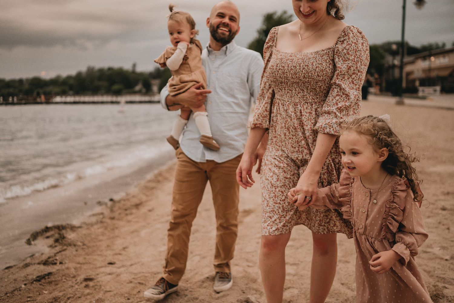 A joyful family enjoying a casual photo session on the beach at sunset.